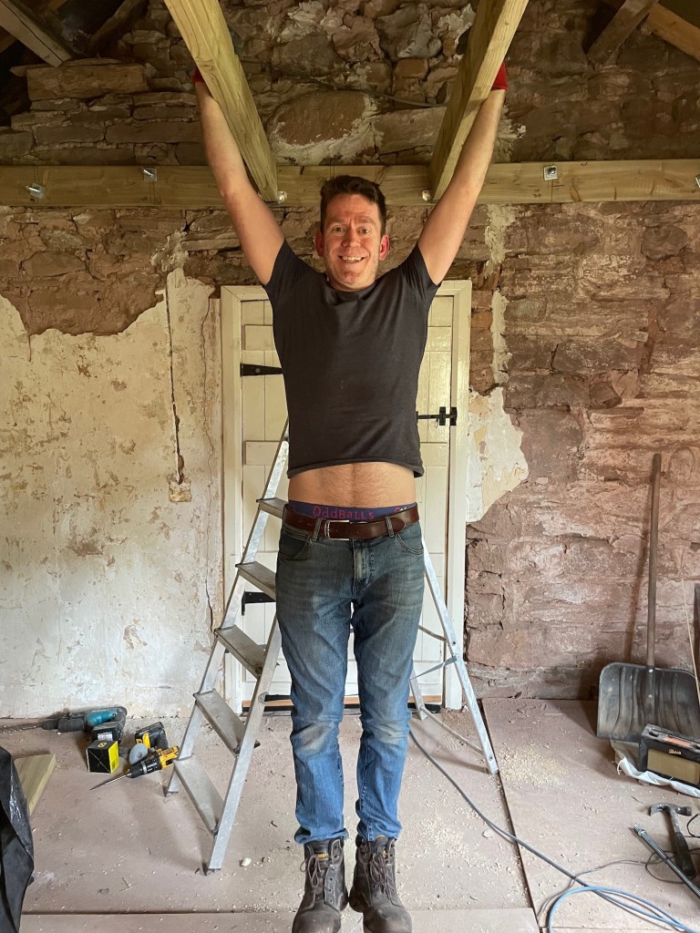 Joe hangs by his hands from two of the new ceiling joists